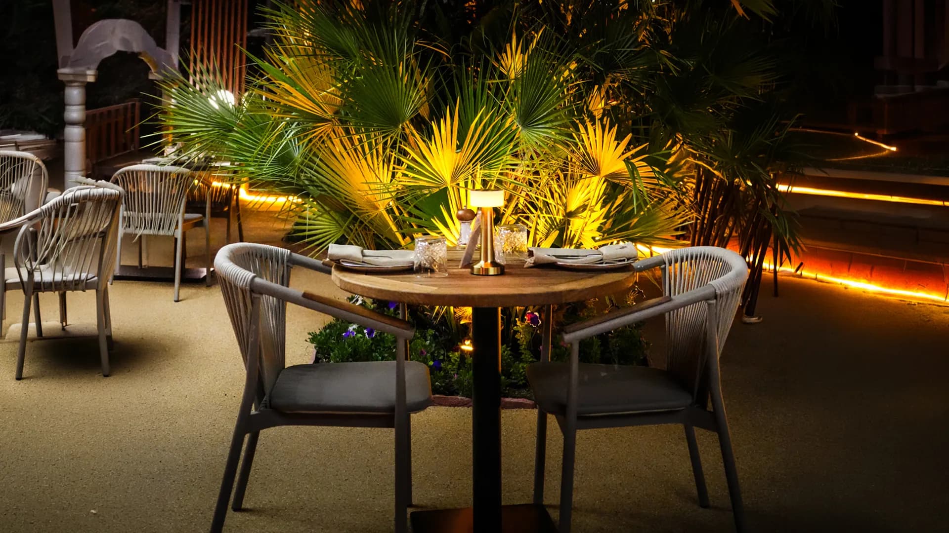 D'ORO terrace at dusk with candlelit tables and lush greenery