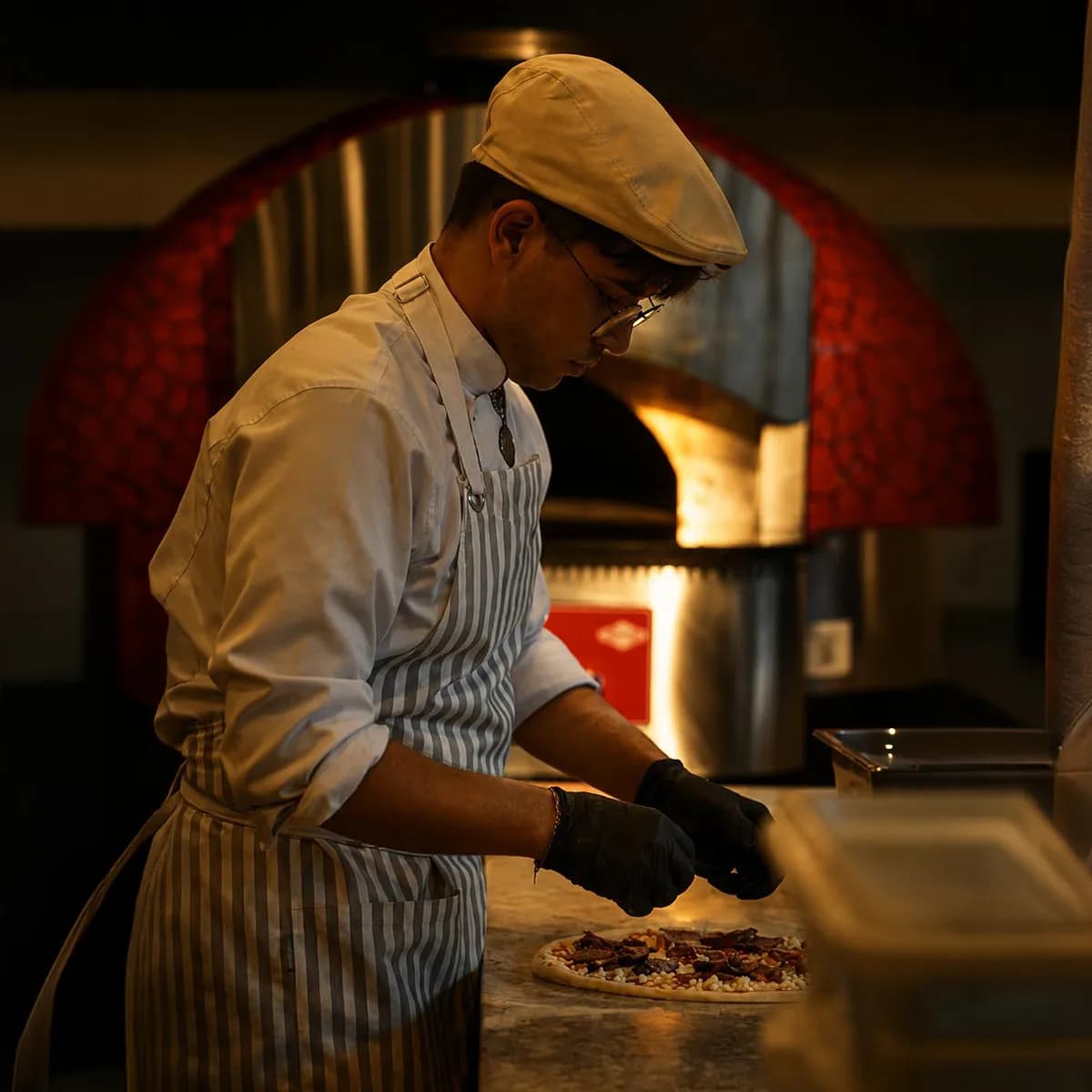 D'ORO chef preparing a pizza at the wood-fired oven